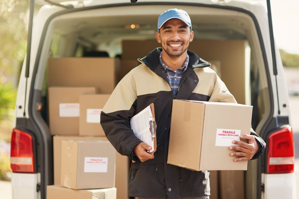 Smiling delivery driver standing in front of van holding a package
